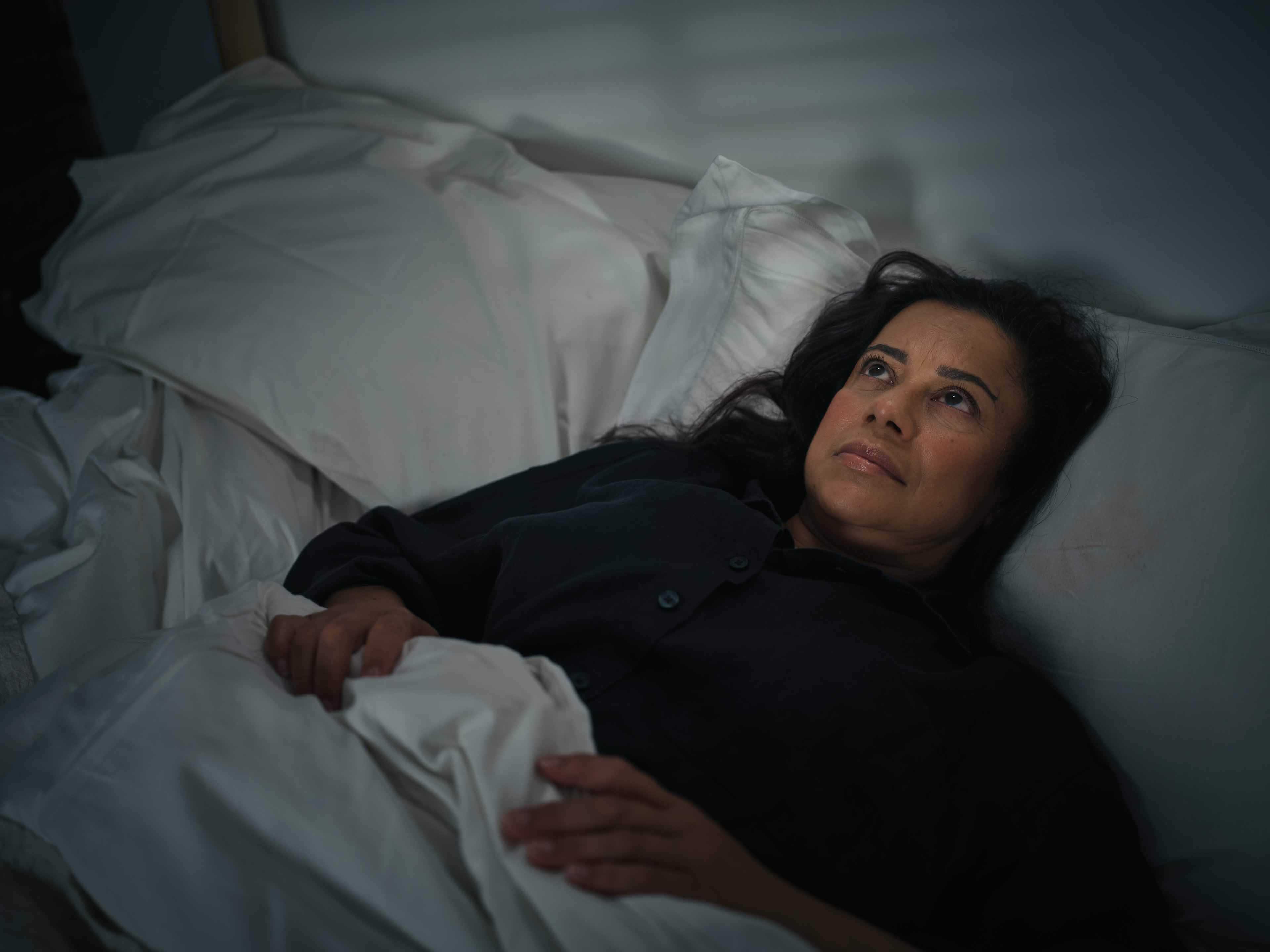 Woman laying in bed staring up at the ceiling late a night unable to sleep