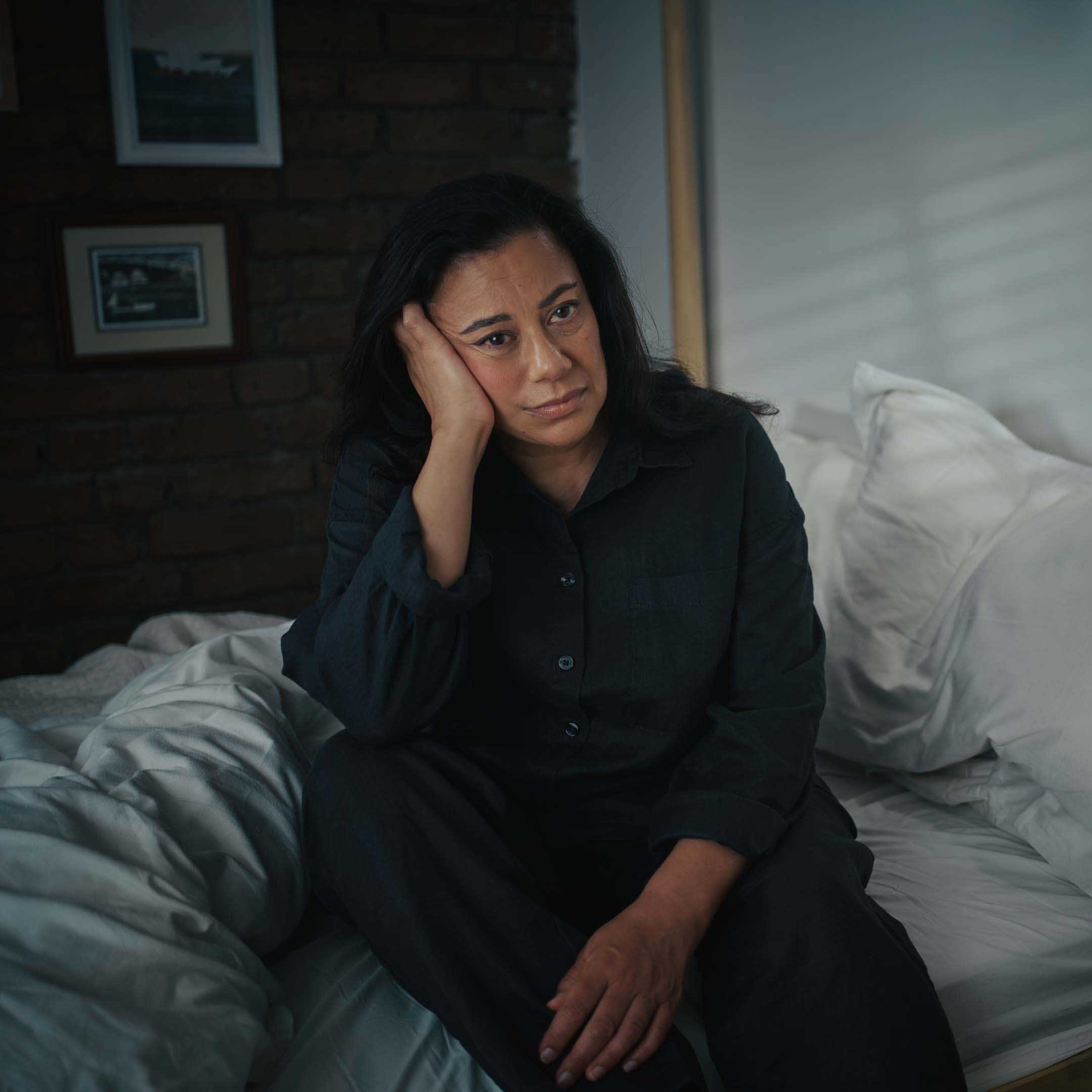 Woman sitting up in bed looking exhausted and sleep deprived